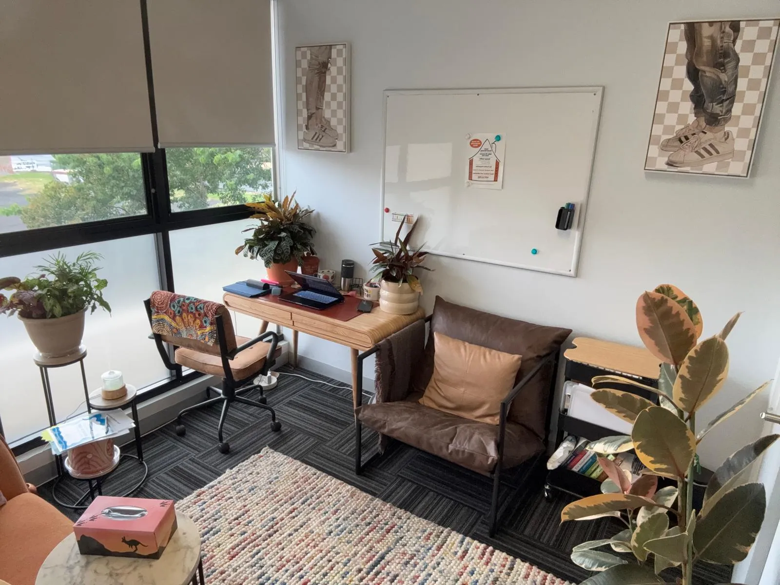 Therapy room desk by the window — chair, plants, soft natural light
